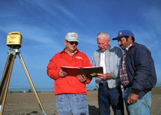 Three men consulting a workplan in the field