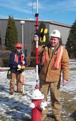 Des employés municipaux en casques de chantier utilisent un équipement GPS pour noter l’emplacement d’une bouche d’incendie