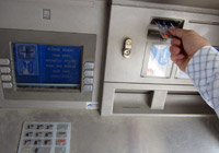 Hand inserting bank card into ATM