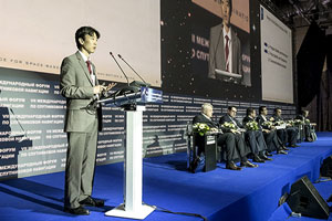 Jason Kim at lectern with other presenters seated on stage