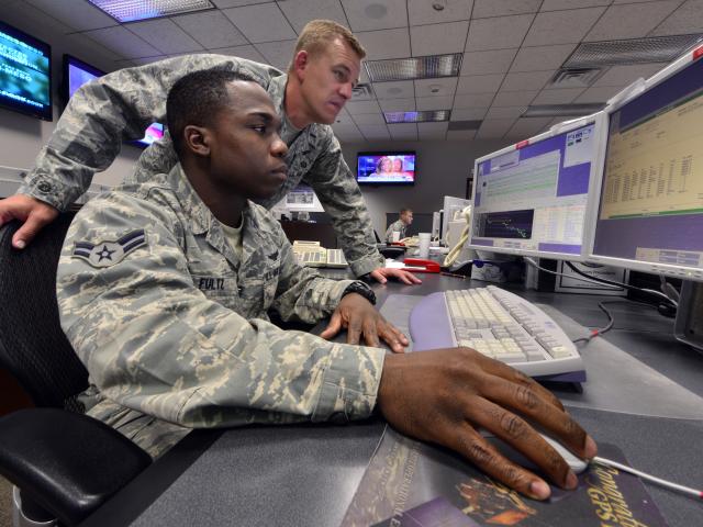 Two operators working at a desk on a computer.