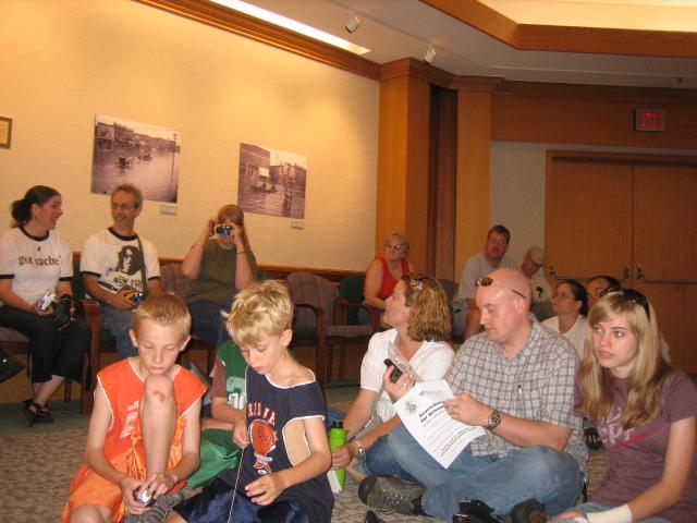 A roomful of people sitting in chairs and on the floor.