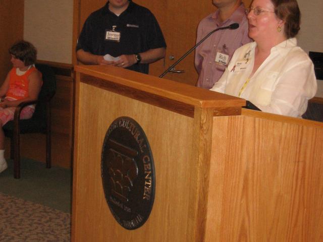 Minnetrista CEO Betty Brewer stands behind a podium with others in the background.