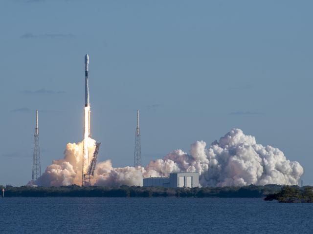 Falcon 9 rocket launching from the ground with a large plume of smoke.