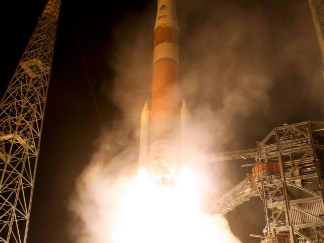 Rocket launching at night with fire and smoke from engines.